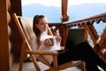 Young attractive business woman is working on the laptop at mountain resort with a cup of tea and cookie. Female relaxes Royalty Free Stock Photo