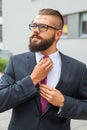 Young attractive businessman adjusting his tie. Outdoor photo. Royalty Free Stock Photo