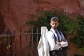 Young and attractive businessman, bearded, suit and tie, with his arms crossed and his jacket leaning on a metal grille, serious