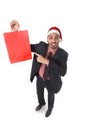 Young attractive businessman in Christmas Santa hat holding and pointing red shopping bag in December and New year sale Royalty Free Stock Photo