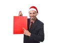 Young attractive businessman in Christmas Santa hat holding and pointing red shopping bag in December and New year sale Royalty Free Stock Photo