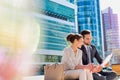 Young attractive businessman discussing business plans over document with beautiful businesswoman while sitting on bench against Royalty Free Stock Photo