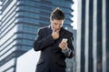 Young attractive businessman in suit and necktie looking text message at mobile phone outdoors Royalty Free Stock Photo