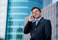 Young attractive businessman in suit and tie talking on mobile phone happy outdoors Royalty Free Stock Photo