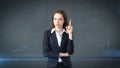 Young attractive businesswoman portrait in suit with standing and finger up, studio background with copyspace. Royalty Free Stock Photo