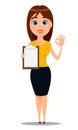 Young attractive businesswoman in smart casual clothes standing with clipboard and showing OK gesture