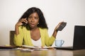 Young attractive and busy black afro American business woman working at home office computer desk talking on the phone holding cal Royalty Free Stock Photo