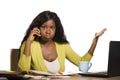 Young attractive and busy black afro American business woman working at home office computer desk talking on the phone stressed is Royalty Free Stock Photo