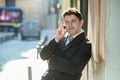 Young attractive and busy businessman with blue eyes wearing suit and tie talking business on mobile phone outdoors Royalty Free Stock Photo