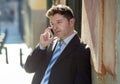 Young attractive and busy businessman with blue eyes wearing suit and tie talking business on mobile phone outdoors Royalty Free Stock Photo