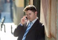 Young attractive and busy businessman with blue eyes wearing suit and tie talking business on mobile phone outdoors Royalty Free Stock Photo