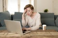 Young attractive and busy woman at home sofa couch doing some laptop computer work in stress looking worried in entrepreneur lifes Royalty Free Stock Photo