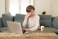 Young attractive and busy woman at home sofa couch doing some laptop computer work in stress looking worried in entrepreneur lifes Royalty Free Stock Photo