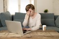 Young attractive and busy woman at home sofa couch doing some laptop computer work in stress looking worried in entrepreneur lifes Royalty Free Stock Photo