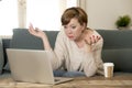 Young attractive and busy woman at home sofa couch doing some laptop computer work in stress looking worried in entrepreneur lifes Royalty Free Stock Photo