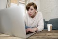 Young attractive and busy woman at home sofa couch doing some laptop computer work in stress looking worried in entrepreneur lifes Royalty Free Stock Photo