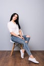 Young attractive calm woman posing on chair against gray background Royalty Free Stock Photo