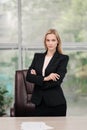 Young attractive Caucasian blond woman in black business suit sits at desk in bright office. Studying paper documents Royalty Free Stock Photo