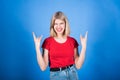 Young and attractive caucasian blonde girl in casual clothes screaming and showing rocker and punk gesture.