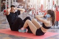 Young attractive Caucasian couple exercising together at gym. Fit man and woman sitting on floor in front of each other and doing Royalty Free Stock Photo