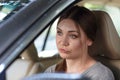 Young attractive caucasian woman behind the wheel driving a car with grimace of disappointment, frustration or displease.