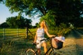 Young attractive caucasian woman with bicycle near horses pasture in summer day at sunset