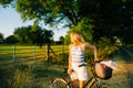 Young attractive caucasian woman with bicycle near horses pasture in summer day at sunset