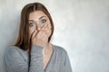 Young attractive caucasian woman covers the mouth with hand, grimace of astonishment or shock. Royalty Free Stock Photo