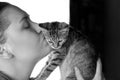 Young attractive caucasian woman kisses little cat of tabby color. Cute kitten as a family member. Royalty Free Stock Photo