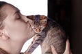 Young attractive caucasian woman kisses little cat of tabby color. Royalty Free Stock Photo