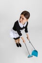 Young attractive chambermaid in uniform brooming floor isolated over white background