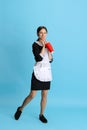 Young attractive chambermaid in uniform drinking soda isolated over blue background