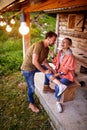 Young attractive cheerful couple burst into laugh in front of wooden cottage. Beuatiful moments. Vacation, holiday, togetherness