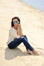 Young attractive cheerful woman sitting on a sand