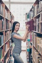 Young attractive clever successful asian female student is putting vocabulary on the book shelf, smiling, so skinny, wearing Royalty Free Stock Photo