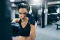 Young attractive coach woman punching a bag with kickboxing gloves training in the gym workout. Sport, fitness, lifestyle and