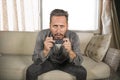 Young attractive concentrated and focused man watching television news or thriller movie sitting at living room sofa couch Royalty Free Stock Photo