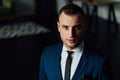 Young attractive and confident businessman in blue suit and black tie.