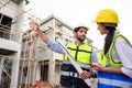 Young attractive construction man and woman in vests with helmets working on the under-construction building site. Home building Royalty Free Stock Photo