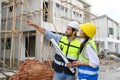 Young attractive construction man and woman in vests with helmets working on the under-construction building site. Home building Royalty Free Stock Photo