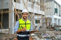 Young attractive construction smiling bearded in vest with white helmet holding laptop and showing thumbs up gesture while Royalty Free Stock Photo