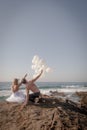 Young attractive couple at beach on rocks with white balloons Royalty Free Stock Photo