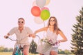 Young attractive couple in glasses riding bikes with balloons Royalty Free Stock Photo