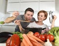 Young attractive couple at home kitchen with man tasting vegetable stew cooked by her wife smiling happy Royalty Free Stock Photo