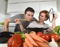 Young attractive couple at home kitchen with man tasting vegetable stew cooked by her wife smiling happy Royalty Free Stock Photo
