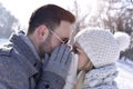 Young attractive couple kissing behind gloved hands in a snowy park Royalty Free Stock Photo