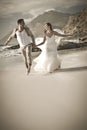 Young attractive couple laughing and running along beach Royalty Free Stock Photo