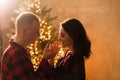 Young attractive couple in love next to Christmas tree, man surprises girlfriend, engagement ring