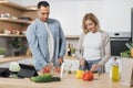 Young attractive couple in love preparing salad from fresh vegetables. Royalty Free Stock Photo