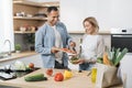 Young attractive couple in love preparing salad from fresh vegetables. Royalty Free Stock Photo